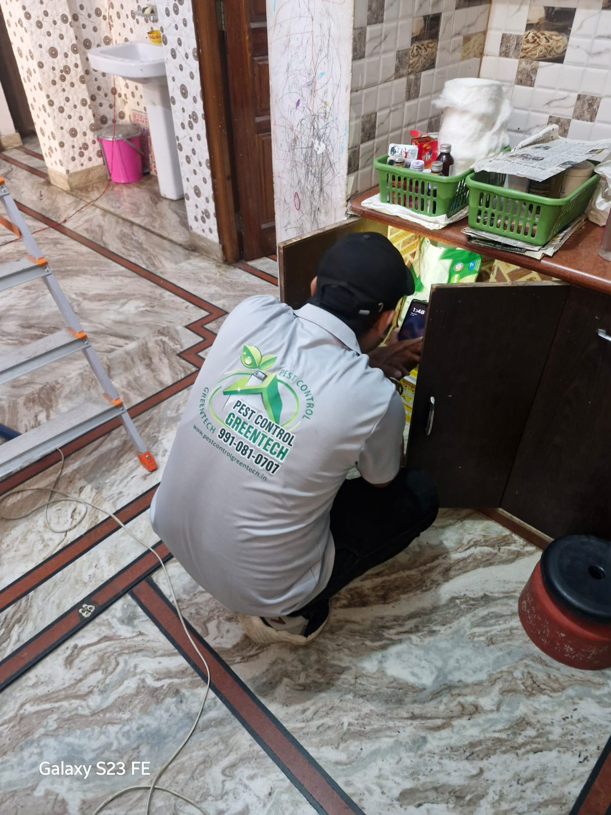 Greentech pest control technician treating a cabinet in a modern home